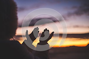 Silhouette of young human hands open palm up worship and praying to god at sunrise, Christian Religion concept background