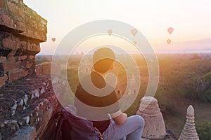 Silhouette of young male backpacker sitting and watching hot air balloon travel destinations in Bagan, Myanmar.