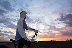 Silhouette of a young man with a Bicycle against the background of a sunset