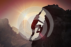 Silhouette of young man climbing on mountain photo