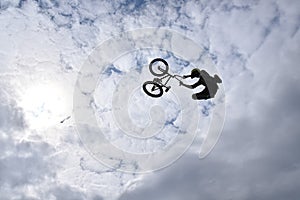 Silhouette of a young man freestyle stunt cyclist flying in the sky