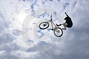 Silhouette of a young man freestyle stunt cyclist flying in the sky