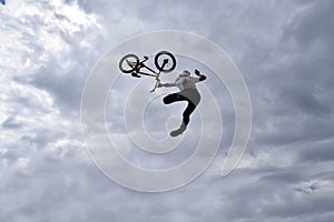 Silhouette of a young man freestyle stunt cyclist flying in the sky