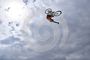 Silhouette of a young man freestyle stunt cyclist flying in the sky performing stunt jump