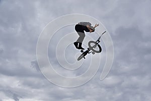 Silhouette of a young man freestyle stunt cyclist flying in the sky performing stunt jump