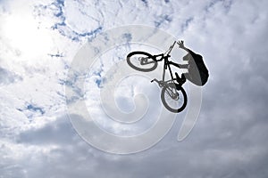 Silhouette of a young man freestyle stunt cyclist flying in the sky performing stunt jump