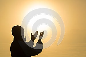 Silhouette of young man hands open palm up worship and praying to god at sunrise, Christian Religion concept background