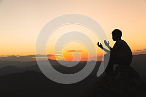 Silhouette of young  man hands open palm up worship and praying to god  at sunrise, Christian Religion concept background