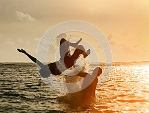 Silhouette of young man jumping out of ocean