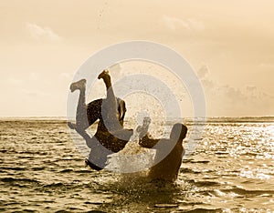 Silhouette of young man jumping out of ocean