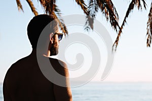 Silhouette of a young man looking at sunset by the sea