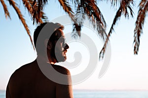 Silhouette of a young man looking at sunset by the sea