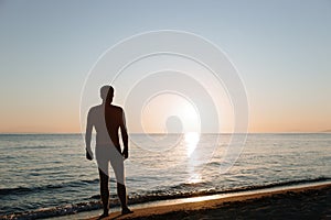 Silhouette of a young man looking at sunset by the sea