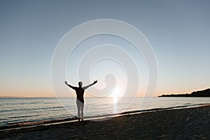 Silhouette of a young man looking at sunset by the sea