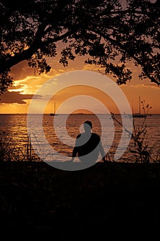 Silhouette of young man meditating on an amazing sunset by the sea