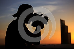 Silhouette young man photographer taking picture on the roof top with sunset sky scene