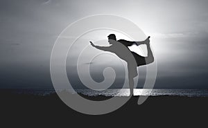 Silhouette of Young Man Practicing Yoga. Sunset on the Seacoast. Standing Bow Pose.