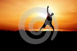 Silhouette of Young Man Practicing Yoga. Sunset on the Seacoast. Trikonasana, Triangle Pose