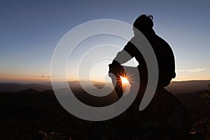 Silhouette of a young man praying to God on the mountain at sunset background. Woman raising his hands in worship. Christian