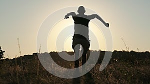 Silhouette of Young Man Running To Sunset Across Field and Jumping in 240 fps
