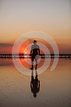 Silhouette of young man by the sea at sunset walking and enjoying freedom and life on summer holiday vacation. Concept