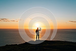 Silhouette of a young man taking pictures of sunset