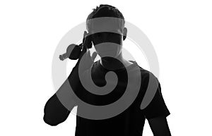 Silhouette of a young man who listens to music attach to ear headphone speakers