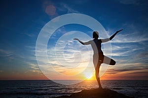 Silhouette young meditation woman practicing yoga on the ocean beach