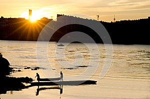 Silhouette of a young men carrying canoe away from lake in sunset