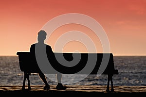 Silhouette of young men sitting alone on the bench