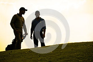 Silhouette of young men standing in golf course with trolley