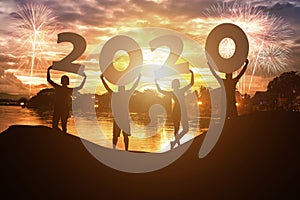 Silhouette young people hold on New year 2020 logo with sky background