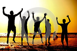 Silhouette of young people jumping on the sea beach