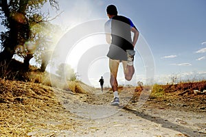 Silhouette of young sport man running off road cross country competition at summer sunset