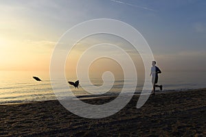 Silhouette young sport man running outdoors on beach at sunset with orange sky