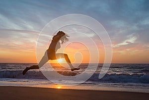 silhouette of a young sporty woman jumping on the beach at sunset