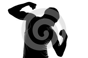 Silhouette of young strong man looking on his biceps.