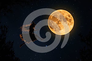 Silhouette of young witch flying in front of big moon