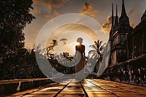 Silhouette of young woman walking at ancient temple at sunset