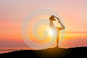 Silhouette of young woman with clipping path practicing yoga relaxing exercise on the mountain top sunset at the beach