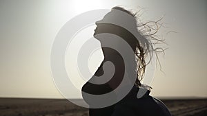 Silhouette of young woman in desert. Girl on railroad track in strong wind.
