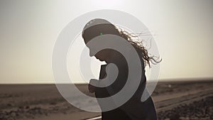 Silhouette of young woman in desert. Girl on railroad track in strong wind.