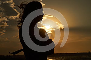Silhouette of a young woman at sunset on the beach