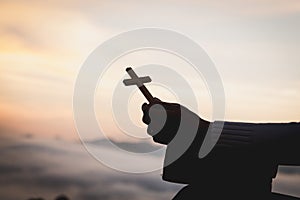 Silhouette of young woman hands holding holy Bible and lift of c