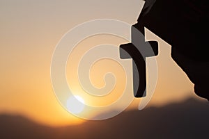 Silhouette of Young woman hands holding holy Bible and lift of christian cross, religion symbol in light and landscape over a