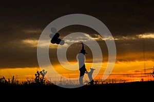 Silhouette of a young woman and her dog at sunset. Outdoors. She is holdings balloons. Love for animals concept