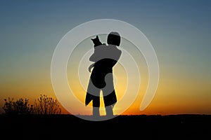 Silhouette Of A Young Woman Holding A Cat At Sunset.