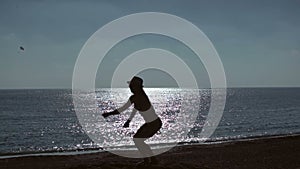 Silhouette of young woman jumping on beach on sea background. slow motion