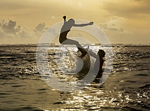 Silhouette of young woman jumping out of ocean