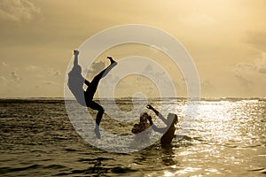 Silhouette of young woman jumping out of ocean